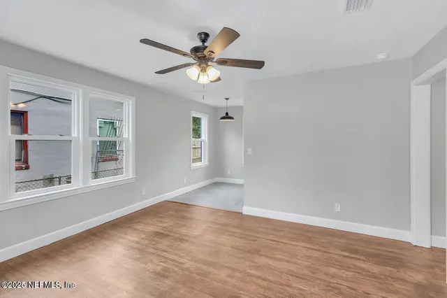 a view of empty room with wooden floor and fan