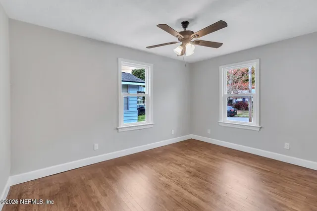 a view of a big room with wooden floor and windows