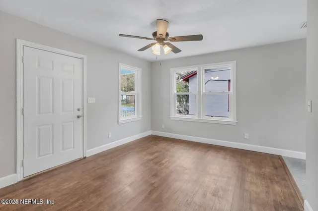 an empty room with wooden floor chandelier and windows