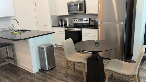 a kitchen with stainless steel appliances granite countertop a dining table chairs a refrigerator and a stove