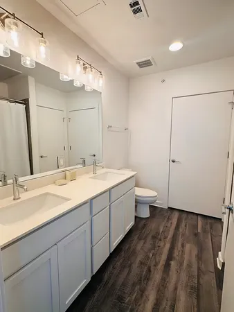 a spacious bathroom with a double vanity sink toilet and a mirror