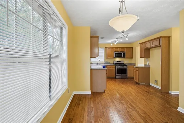 a kitchen with stainless steel appliances granite countertop a refrigerator a stove top oven a sink dishwasher and white cabinets with wooden floor