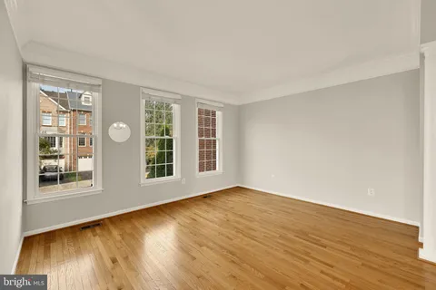 a view of an empty room with wooden floor and windows