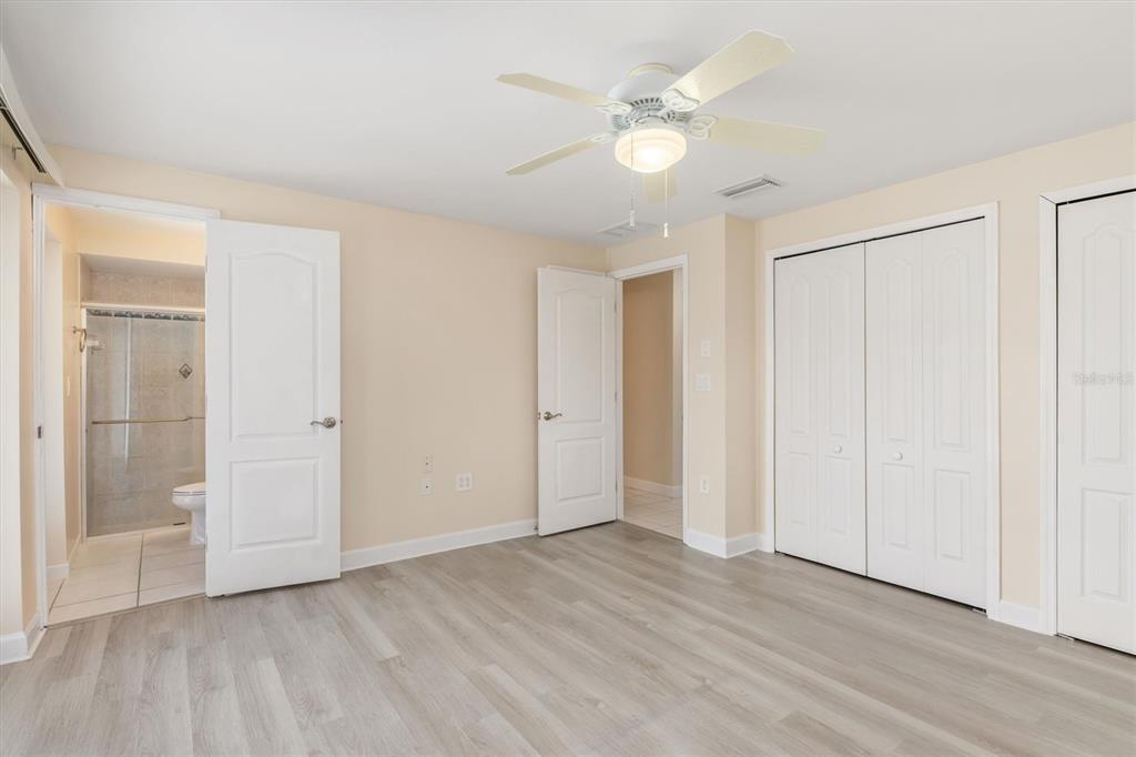 703 Spring Lake Boulevard Northwest Port Charlotte, FL 33952 - Photo 14 of 36 an empty room with wooden floor and ceiling fan