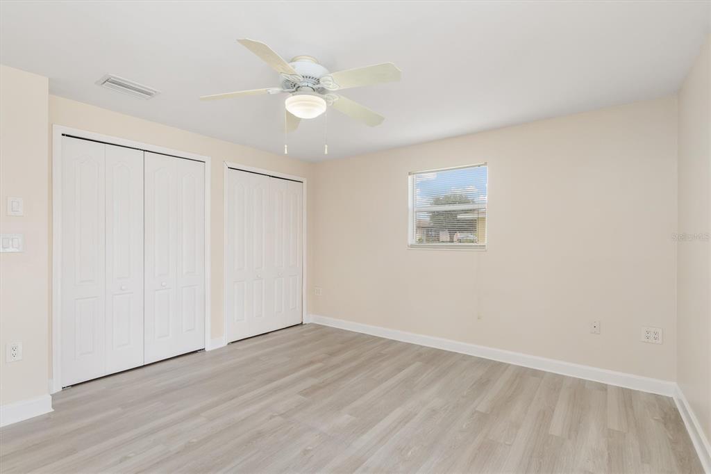 703 Spring Lake Boulevard Northwest Port Charlotte, FL 33952 - Photo 15 of 36 an empty room with wooden floor and fan