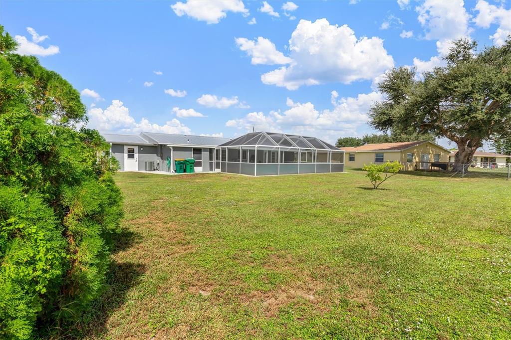 703 Spring Lake Boulevard Northwest Port Charlotte, FL 33952 - Photo 28 of 36 a view of a house with a big yard and potted plants