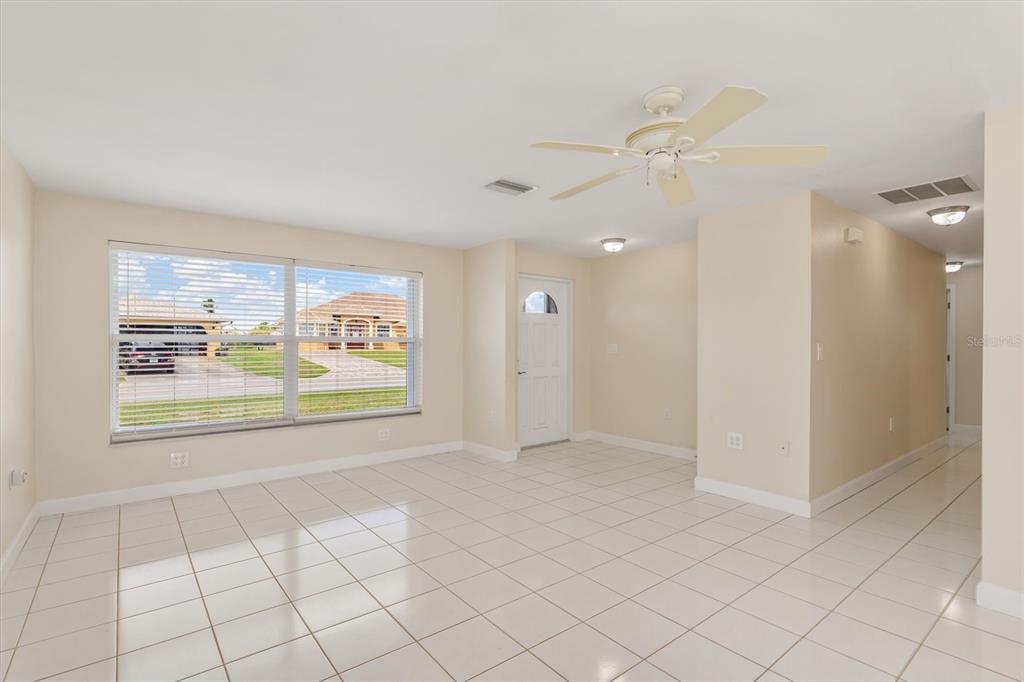 703 Spring Lake Boulevard Northwest Port Charlotte, FL 33952 - Photo 3 of 36 an empty room with windows and view of kitchen