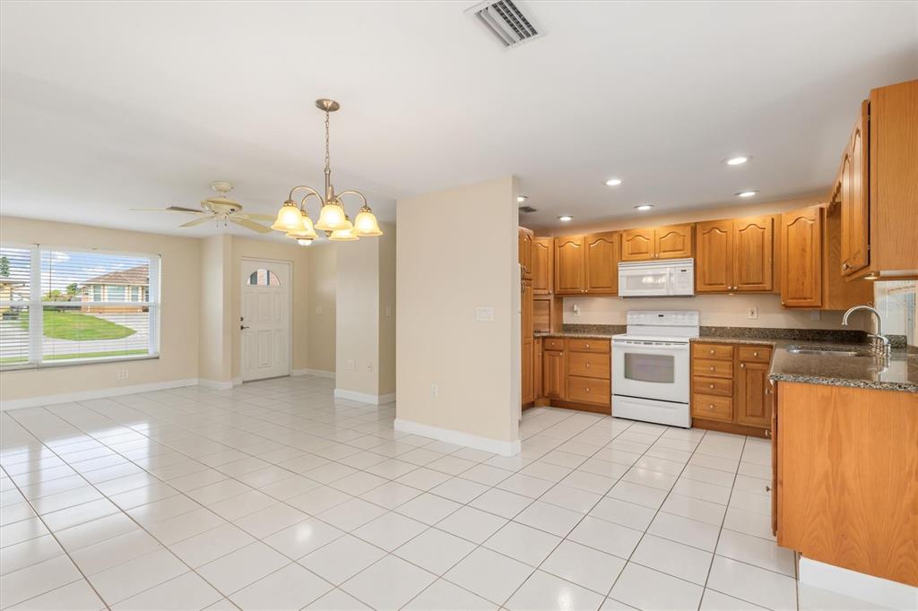 703 Spring Lake Boulevard Northwest Port Charlotte, FL 33952 - Photo 8 of 36 a view of a kitchen with kitchen island granite countertop a stove a sink dishwasher and a cabinets with wooden floor