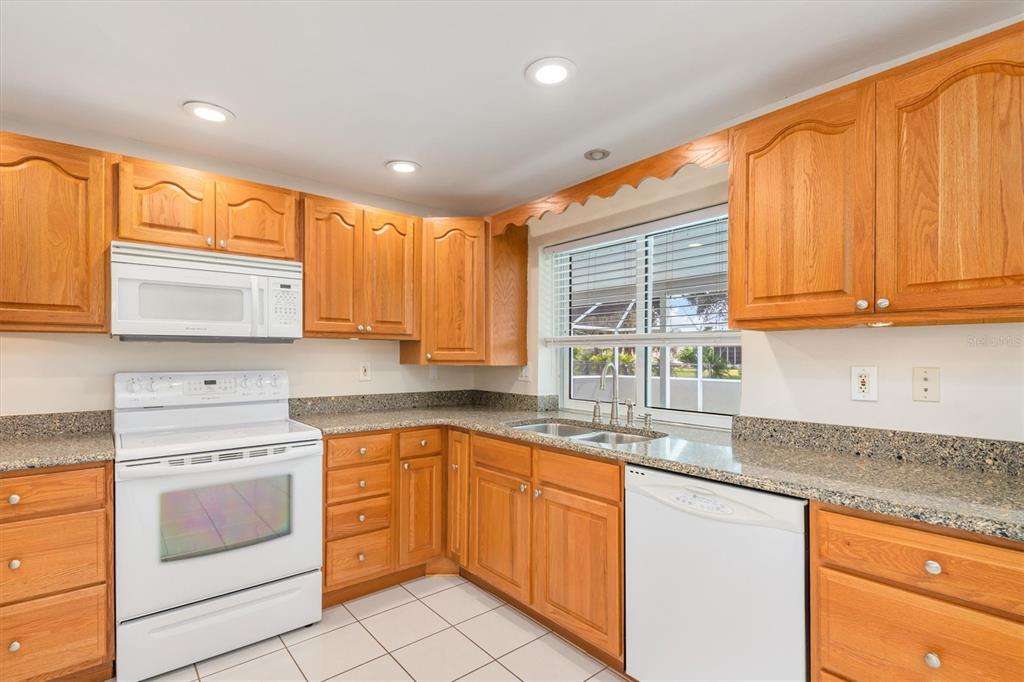 703 Spring Lake Boulevard Northwest Port Charlotte, FL 33952 - Photo 10 of 36 a kitchen with granite countertop wooden cabinets stainless steel appliances a sink and a window