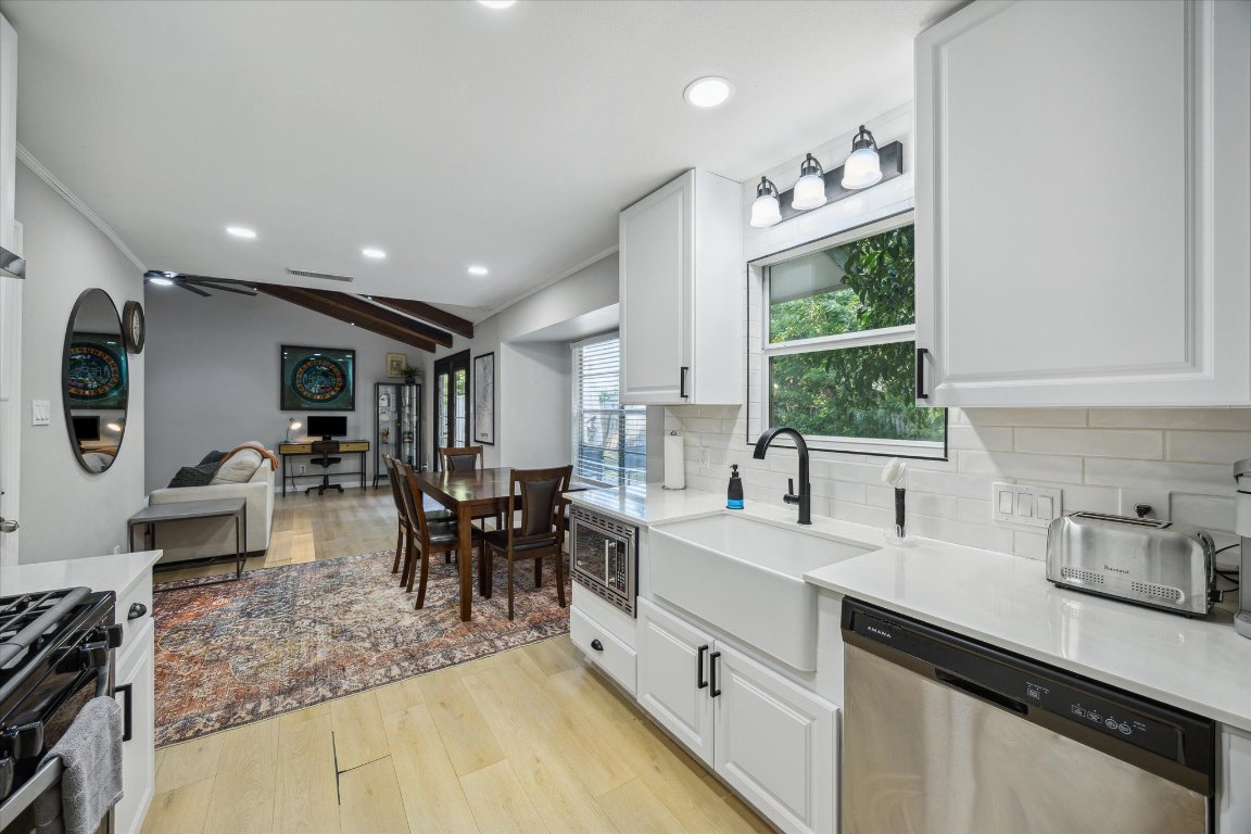 10414 Quail Ridge Drive Austin, TX 78758 - Photo 4 of 17 a large white kitchen with stainless steel appliances granite countertop a sink dishwasher a stove and a dining table with wooden floor
