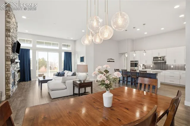 a dining room with wooden floor a chandelier a glass table and chairs