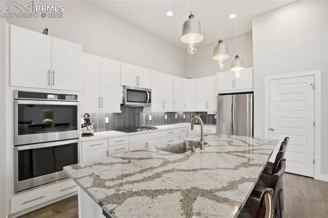 a kitchen with stainless steel appliances kitchen island granite countertop a stove a sink a microwave a refrigerator cabinets and dining table