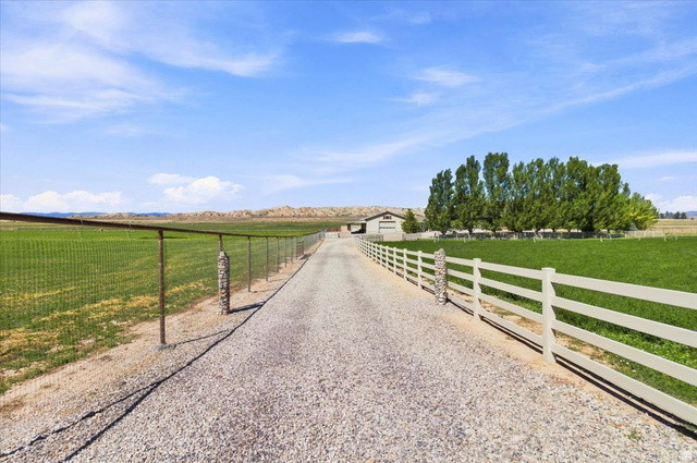 11290 South Southfield Road Mayfield, UT 84643 - Photo 42 of 103 Gravel driveway with a white split-rail fence, leading to a distant building