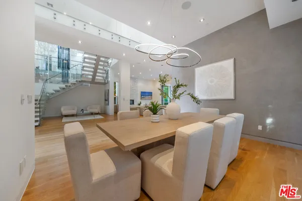 a dining room with stainless steel appliances furniture a rug and a chandelier