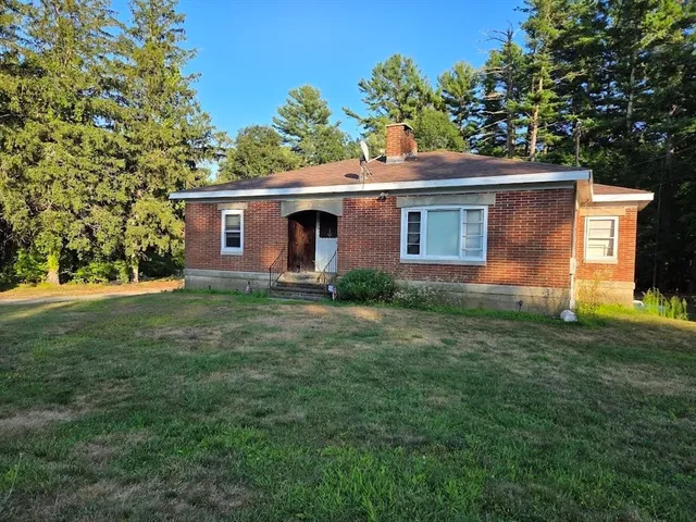 a front view of house with yard and trees in the background