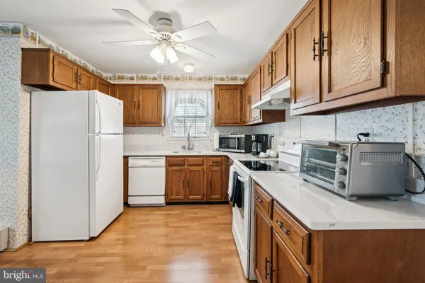 a kitchen with stainless steel appliances granite countertop a sink a stove a refrigerator cabinets and chairs