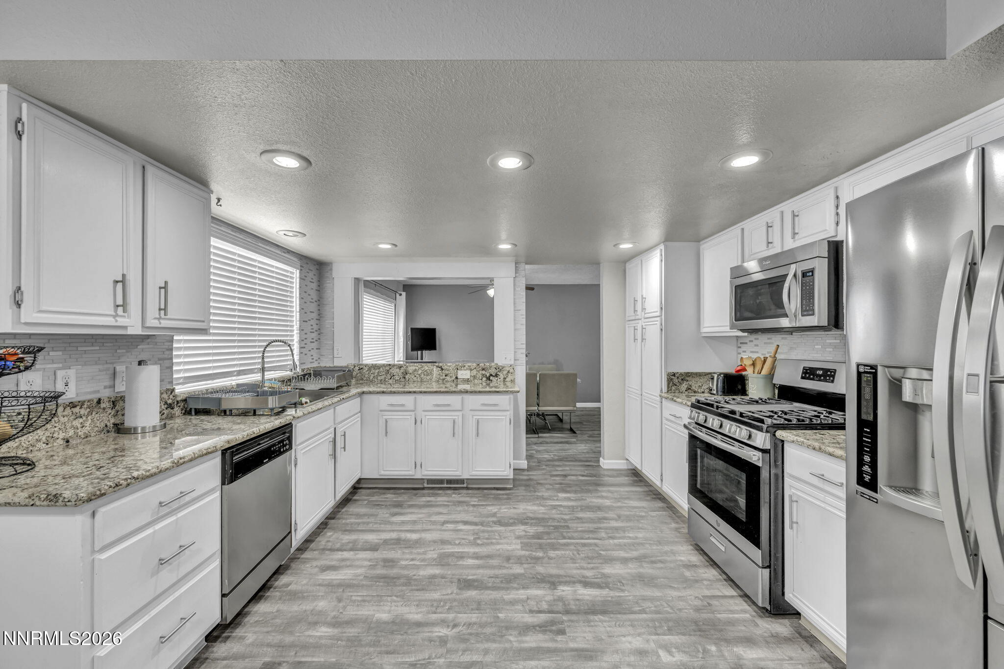 8655 Silver Shores Drive Reno, NV 89506 - Photo 12 of 42 a large kitchen with stainless steel appliances kitchen island granite countertop a stove top oven a sink dishwasher a refrigerator and cabinets with wooden floor