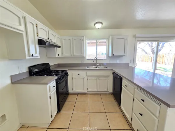 a kitchen with a sink dishwasher stove and white cabinets with wooden floor
