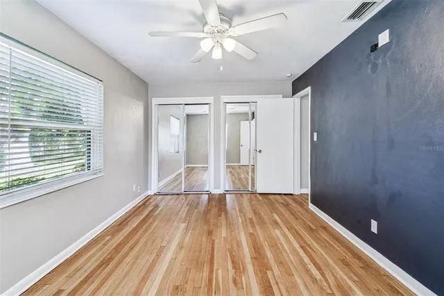 a view of empty room with wooden floor and fan