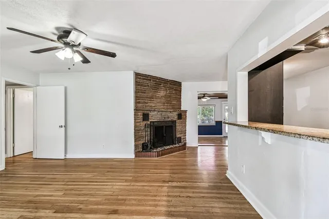 a view of a livingroom with wooden floor a ceiling fan and staircase