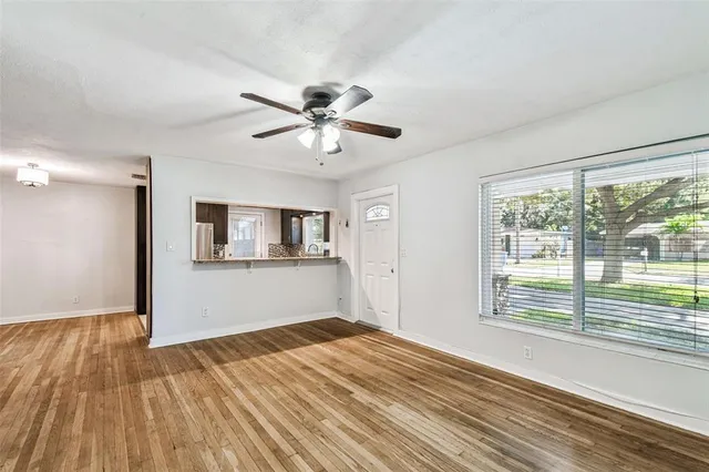 a view of empty room with wooden floor and fan