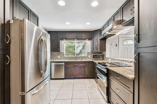 a kitchen with stainless steel appliances granite countertop a refrigerator a stove and a sink
