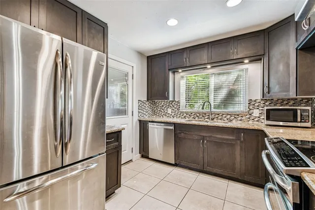 a kitchen with stainless steel appliances granite countertop a refrigerator a sink and a stove