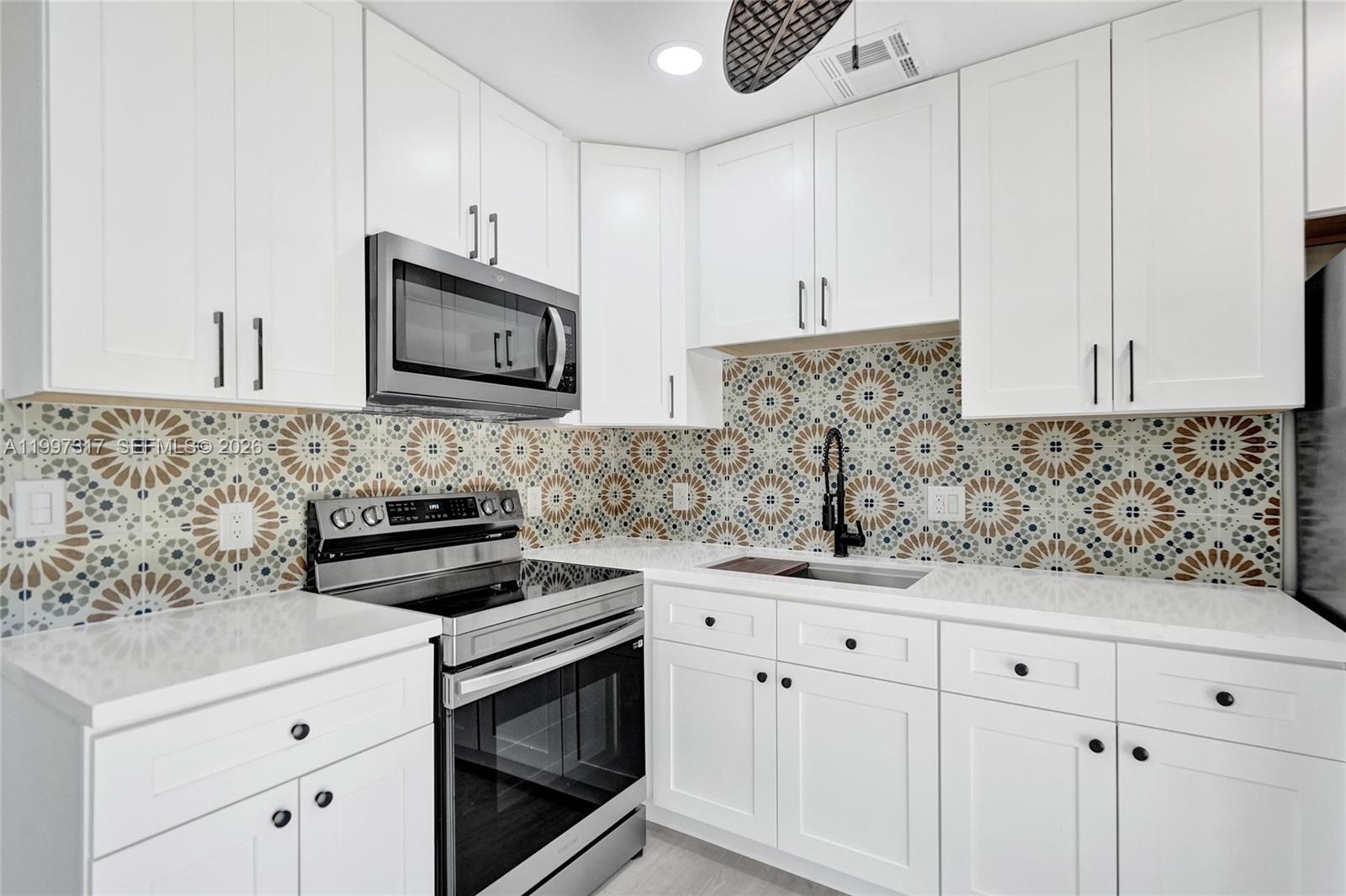 136 Miami Gardens Road West Park, FL 33023 - Photo 19 of 44 a kitchen with white cabinets stainless steel appliances and sink