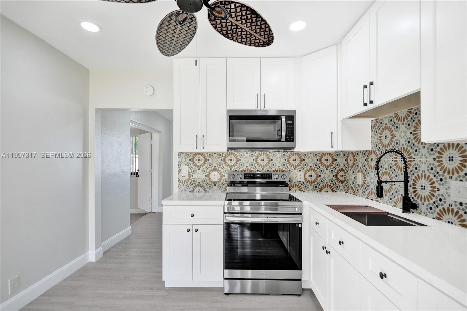 136 Miami Gardens Road West Park, FL 33023 - Photo 20 of 44 a kitchen with stainless steel appliances kitchen island a white stove top oven and sink