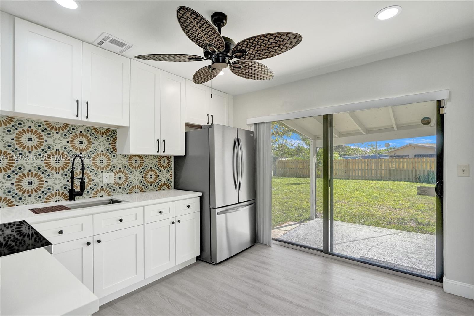 136 Miami Gardens Road West Park, FL 33023 - Photo 2 of 44 a kitchen with granite countertop a refrigerator a sink and white cabinets