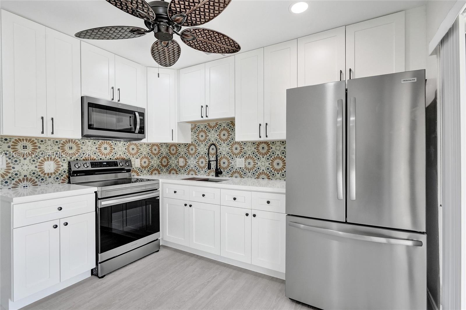 136 Miami Gardens Road West Park, FL 33023 - Photo 7 of 44 a kitchen with stainless steel appliances granite countertop a refrigerator a stove a sink and white cabinets