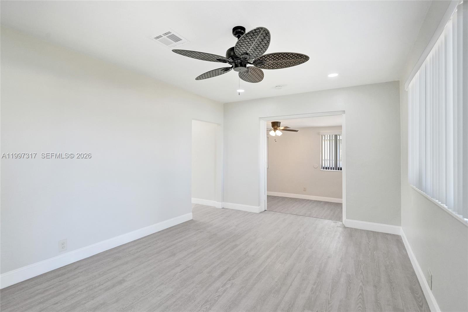 136 Miami Gardens Road West Park, FL 33023 - Photo 9 of 44 a view of an empty room with wooden floor and a ceiling fan