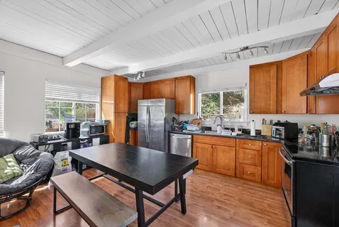 a living room with stainless steel appliances furniture a rug and a window