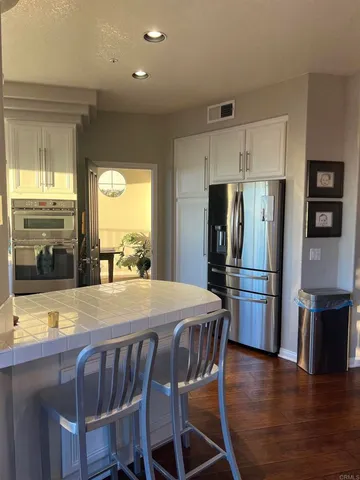 a dining room with stainless steel appliances wooden floors a table and chairs