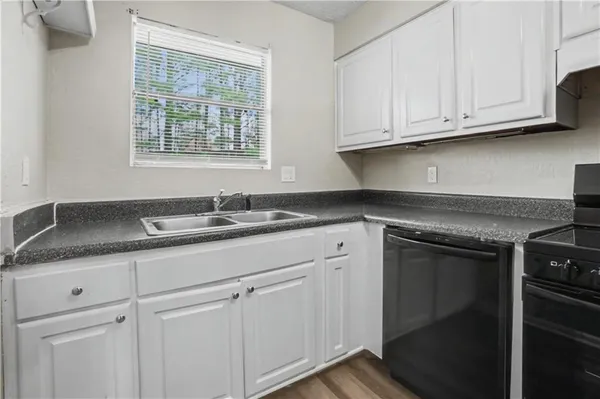 a kitchen with granite countertop white cabinets stainless steel appliances and sink