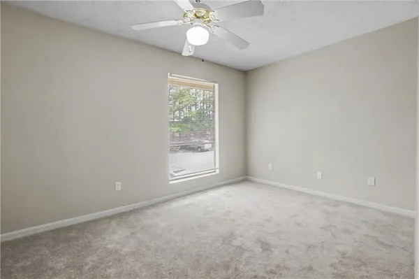 an empty room with windows and fan