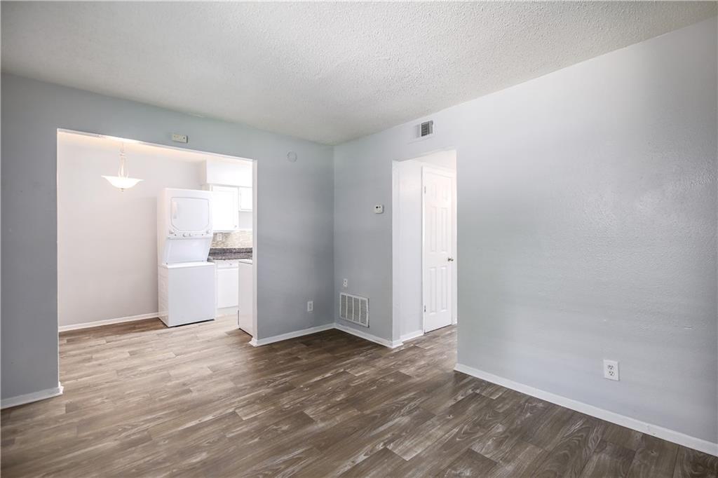 2401 Manor Road, Unit 102 Austin, TX 78722 - Photo 11 of 22 Spare room with stacked washing machine and dryer, a textured ceiling, and dark wood-type flooring