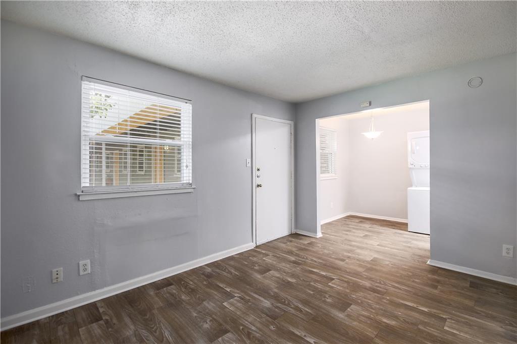 2401 Manor Road, Unit 102 Austin, TX 78722 - Photo 12 of 22 Foyer entrance with dark wood finished floors, a textured ceiling, and stacked washer and dryer