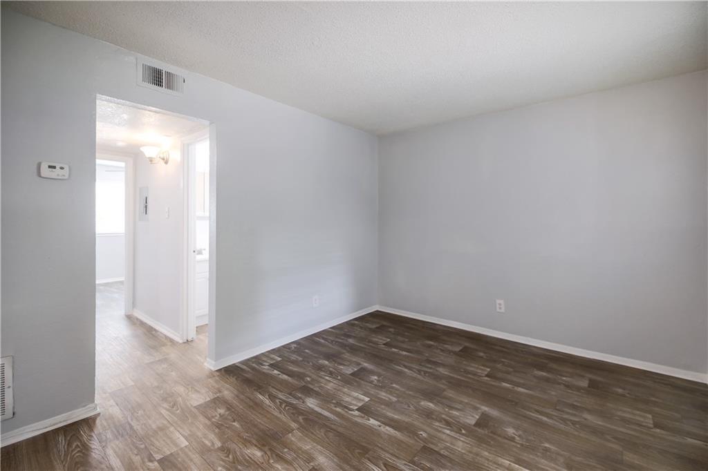 2401 Manor Road, Unit 102 Austin, TX 78722 - Photo 13 of 22 Empty room featuring dark wood finished floors and a textured ceiling