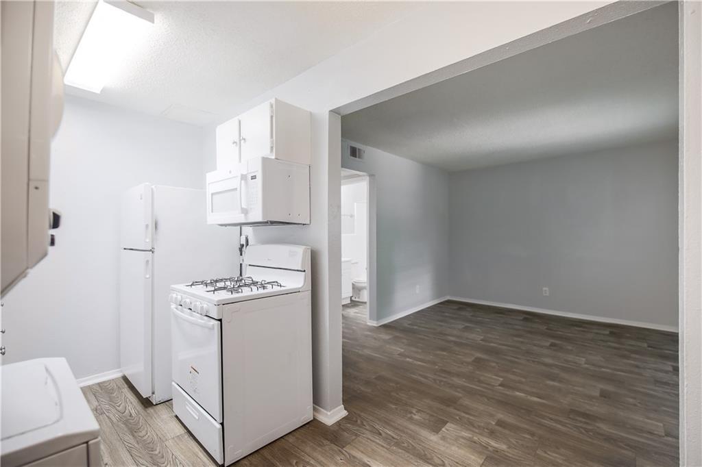 2401 Manor Road, Unit 102 Austin, TX 78722 - Photo 15 of 22 Kitchen featuring white appliances, white cabinetry, light wood-style flooring, and light countertops