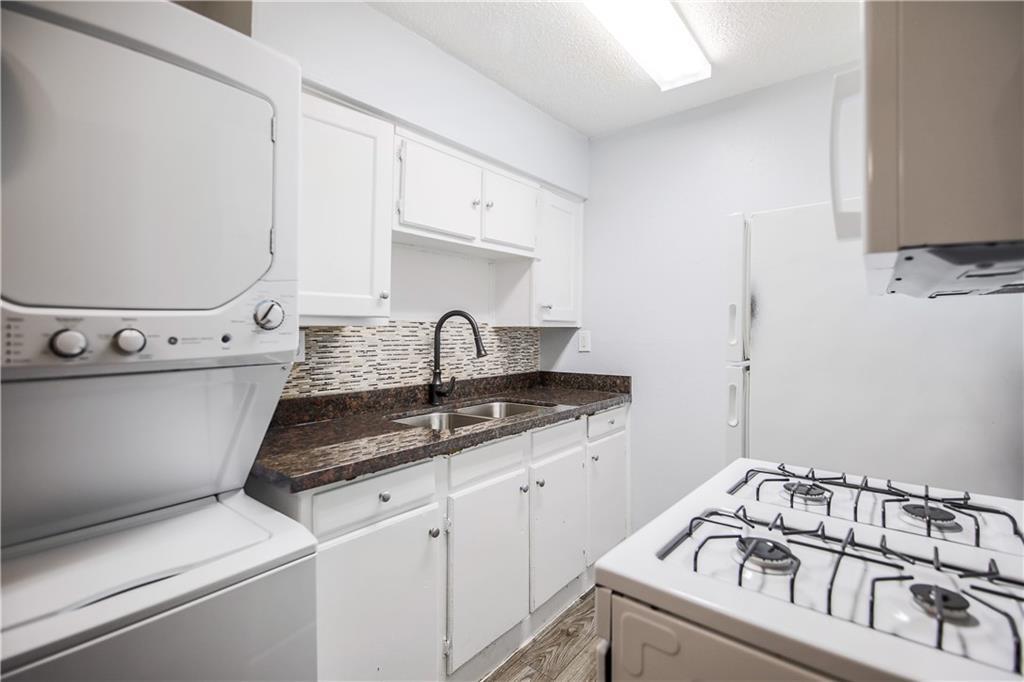 2401 Manor Road, Unit 102 Austin, TX 78722 - Photo 16 of 22 Laundry area with stacked washer and clothes dryer, a textured ceiling, and light wood-type flooring