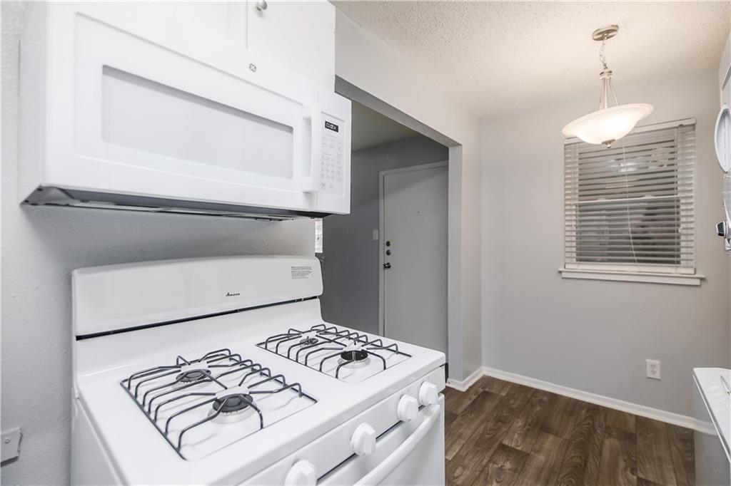 2401 Manor Road, Unit 102 Austin, TX 78722 - Photo 18 of 22 Kitchen with white appliances, a textured ceiling, light countertops, white cabinetry, and dark wood-style flooring