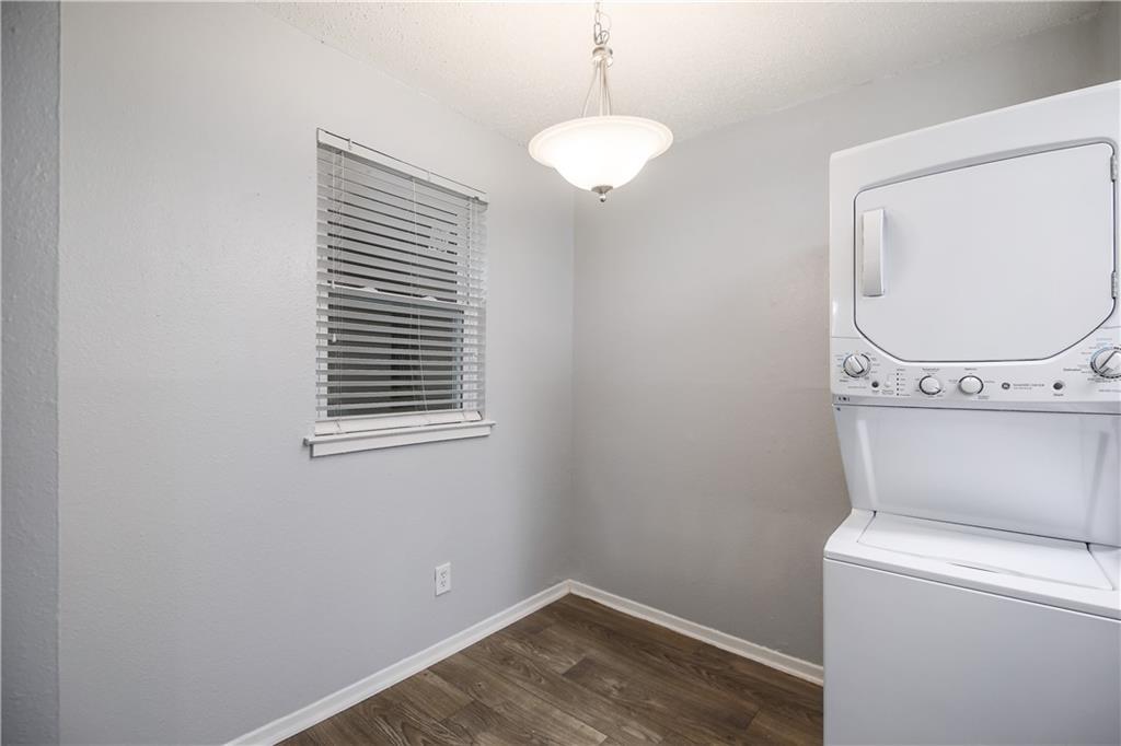 2401 Manor Road, Unit 102 Austin, TX 78722 - Photo 19 of 22 Laundry room featuring dark wood finished floors and stacked washer and clothes dryer