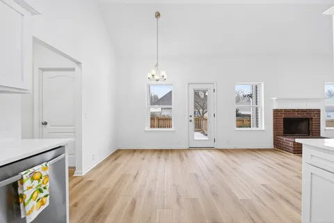 a view of an empty room with window and wooden floor
