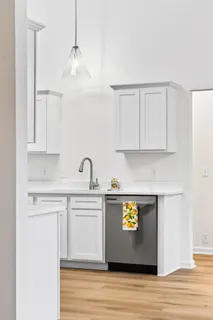 a view of kitchen with stainless steel appliances granite countertop a stove a sink dishwasher and white cabinets with wooden floor