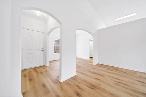 an empty room with wooden floor and entrance