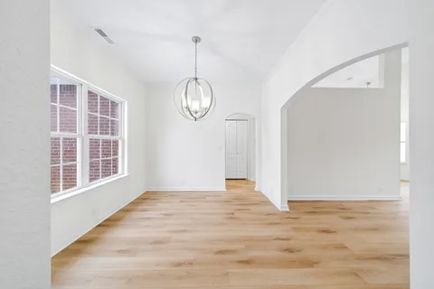 a view of an empty room with wooden floor and window