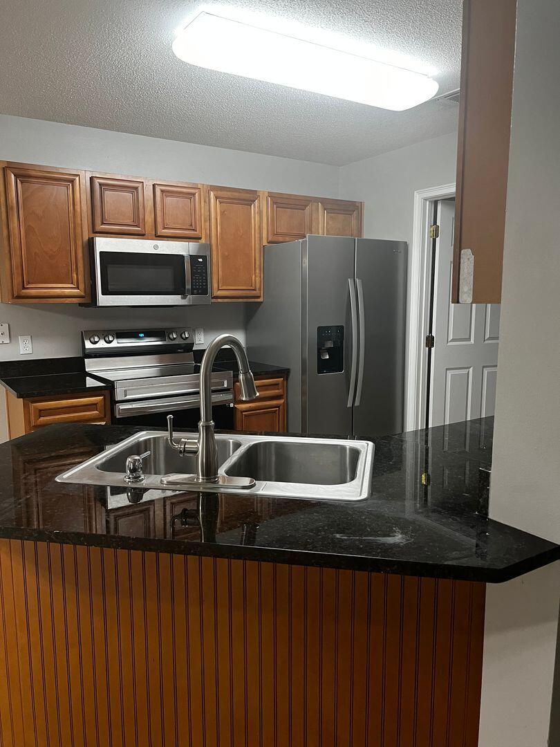 23 3rd Street Shalimar, FL 32579 - Photo 8 of 15 a kitchen with stainless steel appliances granite countertop a stove a sink and a microwave