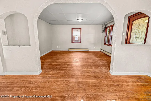a view of an empty room with window and wooden floor