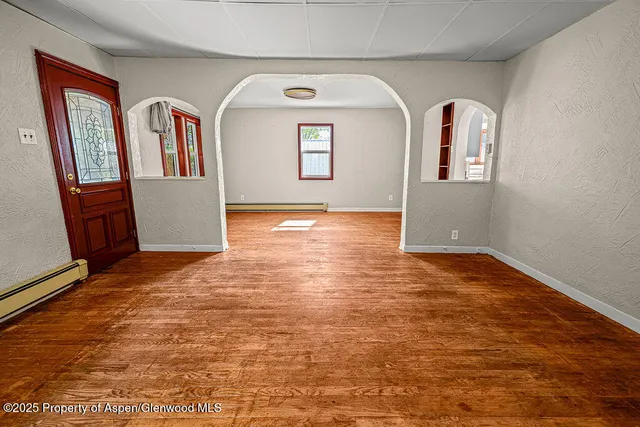 a view of an empty room with window and wooden floor
